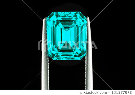 A blue gemstone is being held up by a metal tool 131577978