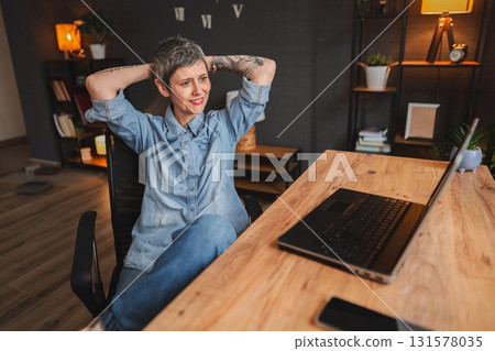 Freelancer relaxing at her desk after finishing work on laptop Freelancer relaxing at her desk after finishing work on laptop 131578035