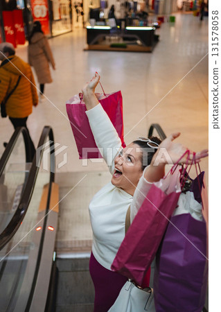 Joyful woman celebrates successful shopping at a bustling mall 131578058
