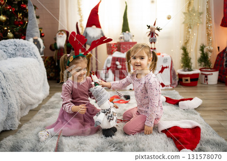 Two adorable children playing with snowman toy near Christmas tree 131578070