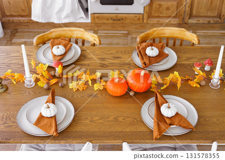 Autumn festive table setting with pumpkins and leaves for seasonal celebration, Halloween decor Autumn festive table setting with pumpkins and leaves for seasonal celebration, Halloween decor 131578355