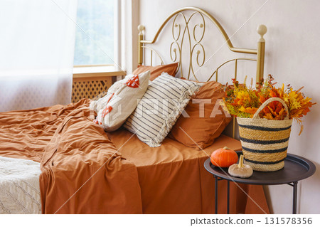 Cozy autumn bedroom interior with warm bedding, pillows, Halloween pumpkins and seasonal decoration Cozy autumn bedroom interior with warm bedding, pillows, Halloween pumpkins and seasonal decoration 131578356