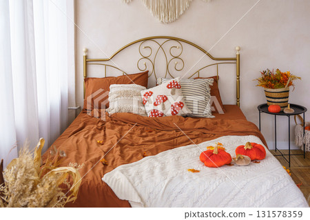 Cozy autumn bedroom interior with warm bedding, pillows, Halloween pumpkins and seasonal decoration 131578359