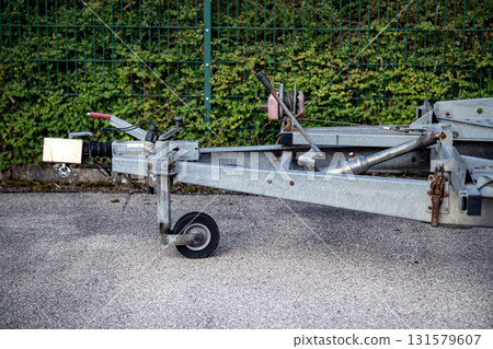 Trailer Hitch Coupling Mechanism On Paved Surface: Close-Up Of Metal Tow Bar With Brake Cable, Rubber Sleeve, And Mounting Hardware For Towing Connection 131579607