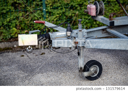 Trailer Hitch Coupling Mechanism On Paved Surface: Close-Up Of Metal Tow Bar With Brake Cable, Rubber Sleeve, And Mounting Hardware For Towing Connection Trailer Hitch Coupling Mechanism On Paved Surface: Close-Up Of Metal Tow Bar With Brake Cable, Rubber Sleeve, And Mounting Hardware For Towing Connection 131579614