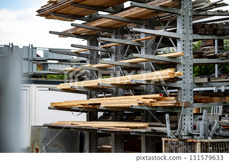 Industrial Storage Racks Holding Various Sizes Of Wooden Planks Outdoors In Construction Yard Under Overcast Sky 131579633