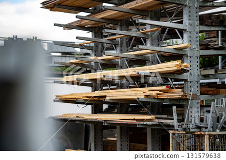 Industrial Storage Racks Holding Various Sizes Of Wooden Planks Outdoors In Construction Yard Under Overcast Sky Industrial Storage Racks Holding Various Sizes Of Wooden Planks Outdoors In Construction Yard Under Overcast Sky 131579638