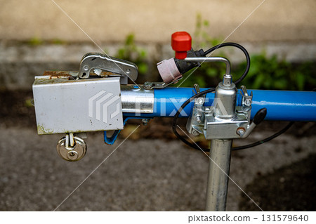 Trailer Hitch Coupling Mechanism On Paved Surface: Close-Up Of Metal Tow Bar With Brake Cable, Rubber Sleeve, And Mounting Hardware For Towing Connection Trailer Hitch Coupling Mechanism On Paved Surface: Close-Up Of Metal Tow Bar With Brake Cable, Rubber Sleeve, And Mounting Hardware For Towing Connection 131579640
