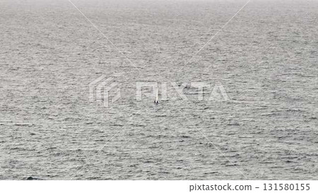 A sailboat drifts on calm waters, capturing serene navigation A sailboat drifts on calm waters, capturing serene navigation 131580155