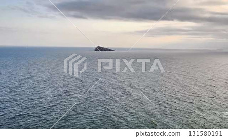 A video shows the oceans beauty from a cliff on a cloudy day 131580191