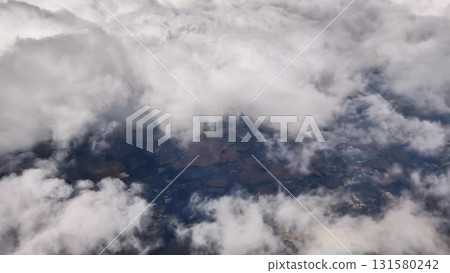 Stunning Aerial View of White Clouds and Varied Landscape as Seen from an Airplane Window 131580242