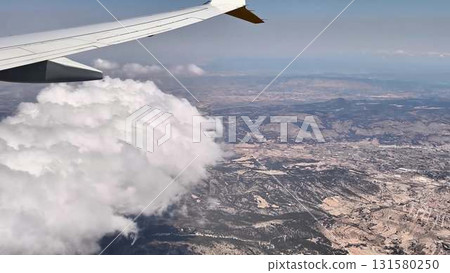 Aerial view reveals beautiful clouds and stunning landscapes from an airplane window 131580250