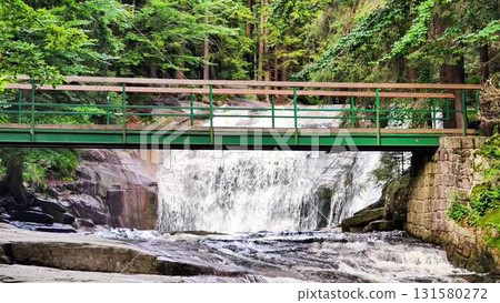 Enjoy a Serene Waterfall View, Complete with a Bridge, Nestled Amidst Lush Greenery Enjoy a Serene Waterfall View, Complete with a Bridge, Nestled Amidst Lush Greenery 131580272