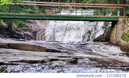 A serene waterscape featuring a beautiful bridge accompanied by a stunning cascading waterfall A serene waterscape featuring a beautiful bridge accompanied by a stunning cascading waterfall 131580278