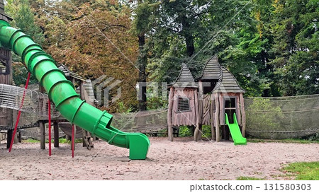 A colorful playground with a large green slide and wooden structures for kids to explore 131580303