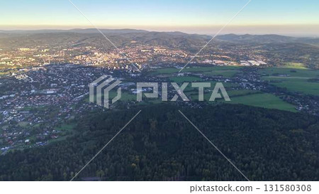 Aerial view of a vibrant city next to lush, green fields, creating a picturesque landscape 131580308
