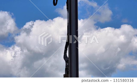 Industrial Machinery Operating Under a Beautiful Blue Sky Filled with Fluffy White Clouds 131580316