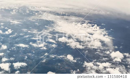 Behold an Aerial View showcasing the magnificent Clouds and Earth from a soaring Airplane 131580418
