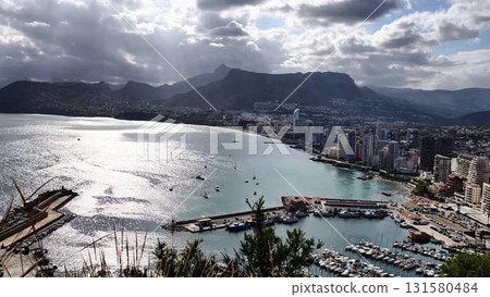Stunning Aerial View of a Beautiful Coastal City Featuring a Marina and Majestic Mountains 131580484
