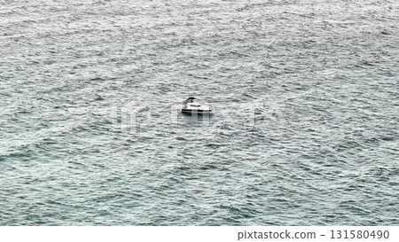 A lonely boat gracefully drifts on the vast open sea, beautifully captured from above 131580490