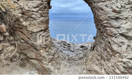 A breathtaking scenic coastal view seen through a stunning archway in a rugged rocky landscape, A breathtaking scenic coastal view seen through a stunning archway in a rugged rocky landscape, 131580492