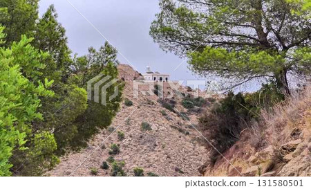 Experience breathtaking views of a hilltop building surrounded by lush greenery, inviting adventure Experience breathtaking views of a hilltop building surrounded by lush greenery, inviting adventure 131580501
