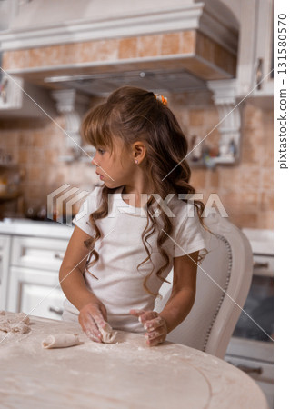 young girl is focused on making a cake. Flour dusts the table as she shapes dough gaining confidence in her baking skills. young girl is focused on making a cake. Flour dusts the table as she shapes dough gaining confidence in her baking skills. 131580570