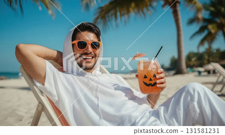 Young man in white hoodie relaxing on beach chair, enjoying Halloween-themed cocktail with pumpkin face, surrounded by palm trees and bright blue sky, celebrating festive spirit in tropical paradise 131581231