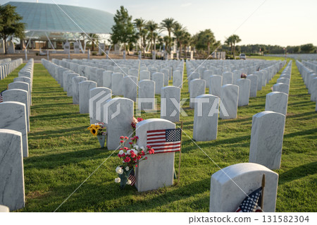 American army national cemetery with rows of white headstones decorated with flowers and USA flags on green grass lawn. Memorial Day concept American army national cemetery with rows of white headstones decorated with flowers and USA flags on green grass lawn. Memorial Day concept 131582304