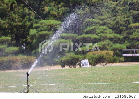公園裡有自動向綠色草坪噴水的灑水器 公園裡有自動向綠色草坪噴水的灑水器 131582668