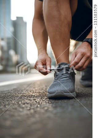 Runner Tying Shoelaces on Urban Street Before Jogging for Fitness and Lifestyle Editorial Use 131583579
