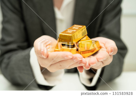Asian woman holding gold bar in finance business. Asian woman holding gold bar in finance business. 131583928