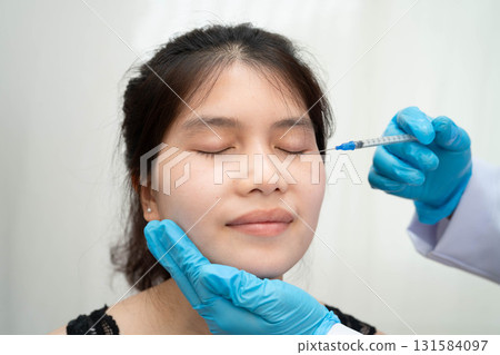 Asian woman receiving plastic surgery shape of nose performed on face. Asian woman receiving plastic surgery shape of nose performed on face. 131584097