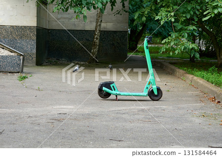 A lonely lost electric scooter in the yard of a house A lonely lost electric scooter in the yard of a house 131584464