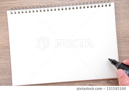 Hand holding a notebook and a black permanent marker 131585100