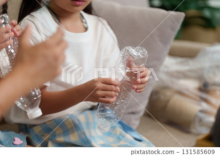 Sustainability and Child Education. Children engage in recycling practices by preparing plastic bottles for disposal. 131585609