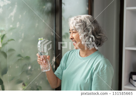 Hydration and Health Awareness. An elderly woman smiling while holding a water bottle, emphasizing the importance of hydration. Hydration and Health Awareness. An elderly woman smiling while holding a water bottle, emphasizing the importance of hydration. 131585665