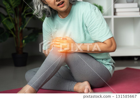 Wellness and Joint Pain Relief. A senior woman experiencing knee pain while exercising on a yoga mat, highlighting the importance of self-care. Wellness and Joint Pain Relief. A senior woman experiencing knee pain while exercising on a yoga mat, highlighting the importance of self-care. 131585667