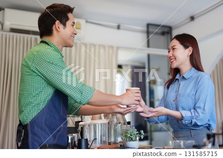 Sustainable Practices and Positive Interactions. A barista serves an eco-conscious customer coffee in a modern cafe. 131585715