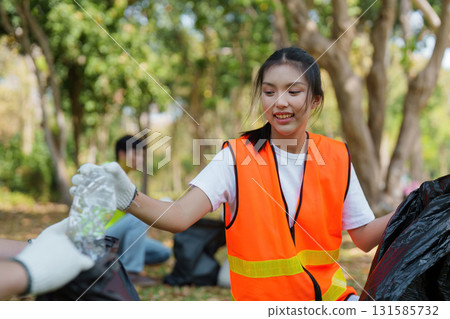 Volunteer smiling while participating in a community cleanup event in a park. 131585732