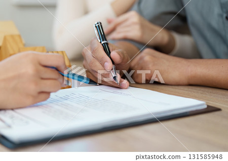 Signing commitment. Close-up of hands signing a real estate contract. 131585948