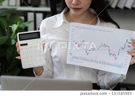 Financial calculations. A professional woman conducting a detailed analysis with a calculator and financial reports. Financial calculations. A professional woman conducting a detailed analysis with a calculator and financial reports. 131585983
