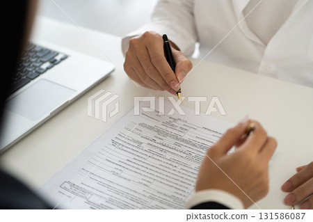 Tax consultant preparing financial documents for a client, emphasizing accuracy and clarity. Tax consultant preparing financial documents for a client, emphasizing accuracy and clarity. 131586087