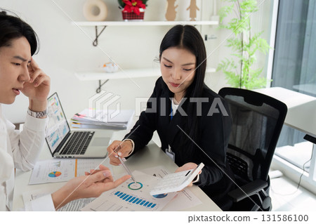 Business professionals collaborating on financial analysis and budgeting in a modern office. 131586100