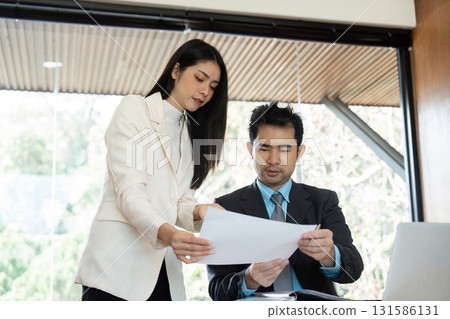 Businesswoman collaborating with a colleague on financial documents Businesswoman collaborating with a colleague on financial documents 131586131