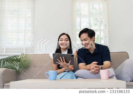 Couple laughing while watching something entertaining on a tablet at home. Couple laughing while watching something entertaining on a tablet at home. 131586133
