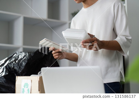 Individual organizing recyclable materials and notepads for donation and recycling. 131586137