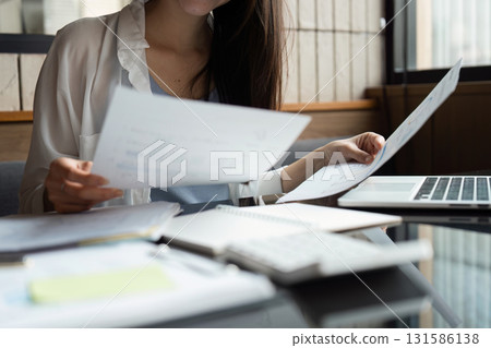 Businesswoman analyzing financial reports in a modern office environment. Businesswoman analyzing financial reports in a modern office environment. 131586138
