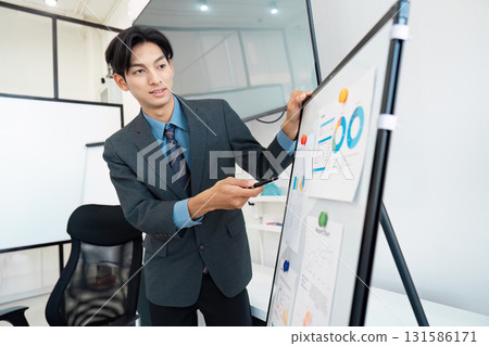 Business professional presenting financial data on a whiteboard during a meeting. Business professional presenting financial data on a whiteboard during a meeting. 131586171