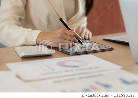 Professional analyzing financial data on a tablet, focusing on charts and calculations. Professional analyzing financial data on a tablet, focusing on charts and calculations. 131586182